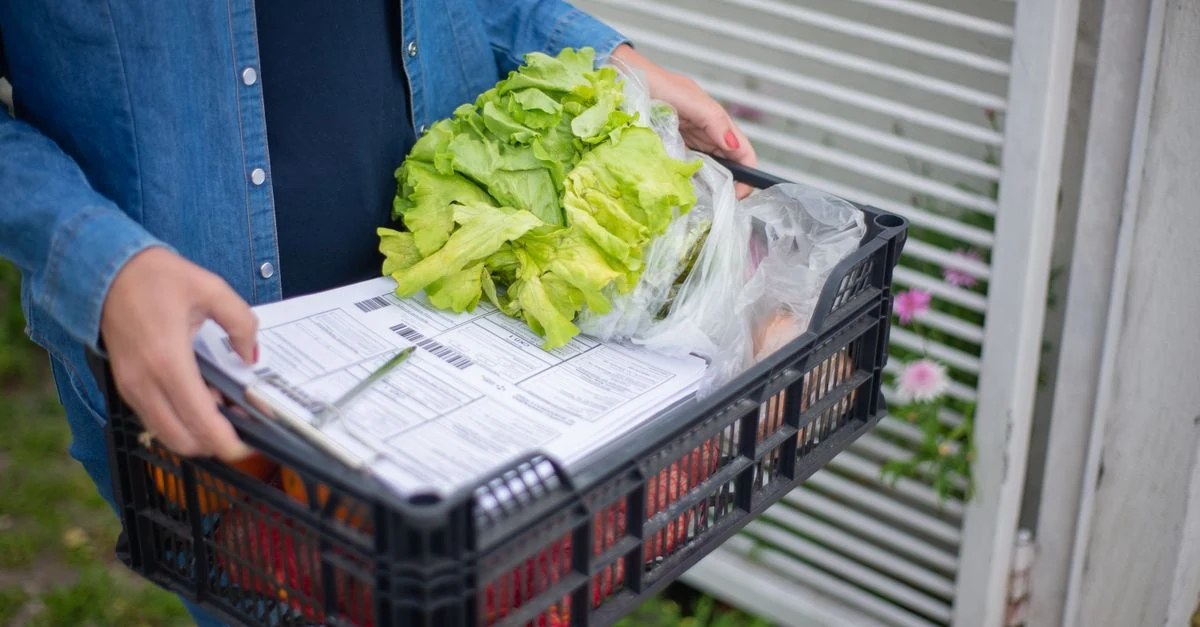 少量の旬野菜が入った宅配ボックスをキッチンで確認する様子